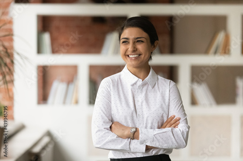 Картината върху платно Successful happy millennial generation young indian ethnicity businesswoman standing in modern office, looking in distance, feeling inspired of new challenges, corporate career opportunities concept