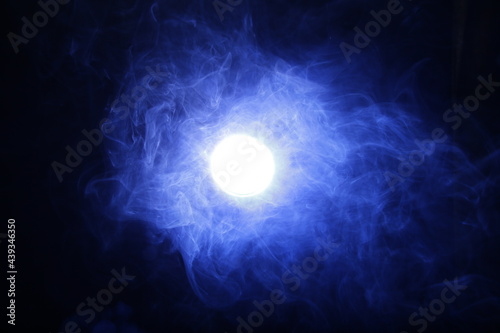 Artificial magic smoke in blue light on black background