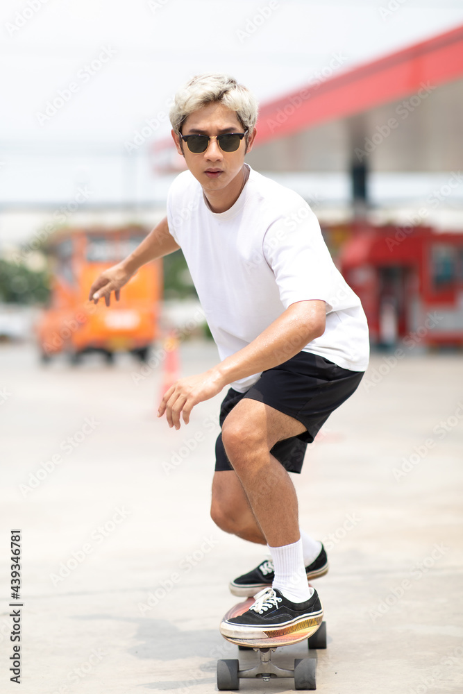 Asian young man playing surfskate or skate board in gas station urban city outdoor. Extream sports