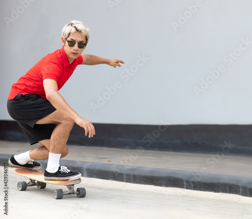 Asian young man playing surfskate or skate board in gas station urban city outdoor. Extream sports