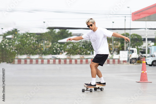 Asian young man playing surfskate or skate board in gas station urban city outdoor. Extream sports © NVB Stocker