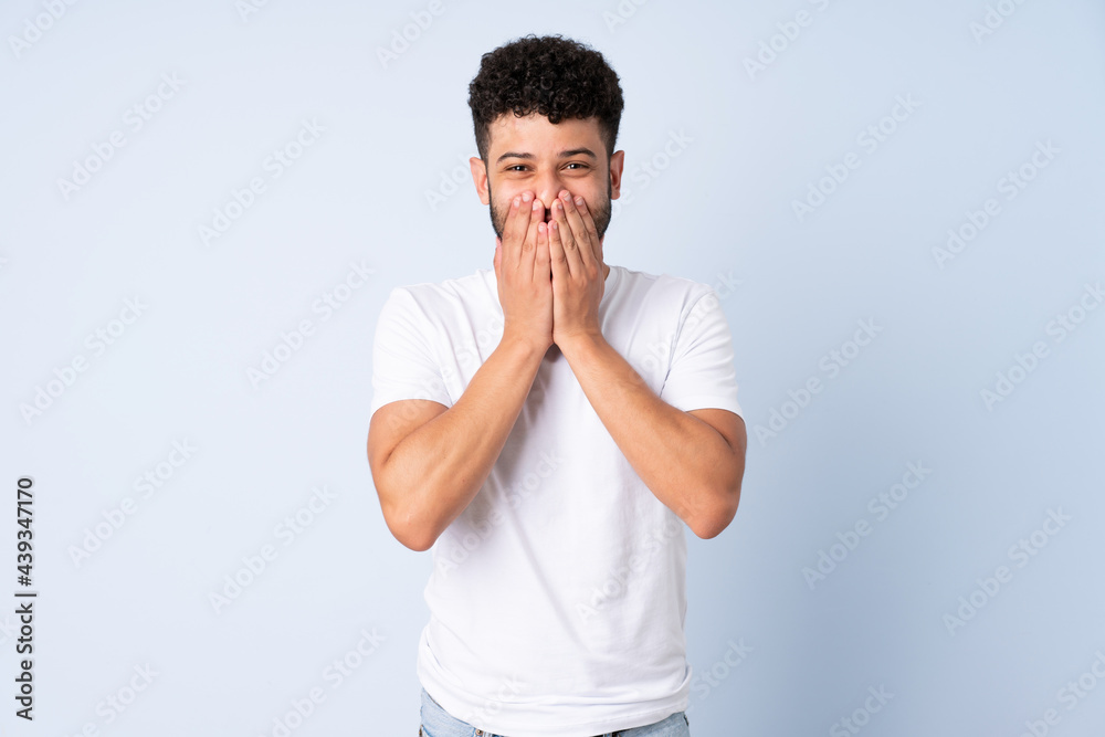 Young Moroccan man isolated on blue background happy and smiling covering mouth with hands Young Moroccan man isolated on blue background happy and smiling covering mouth with hands
