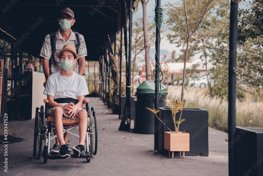 Obraz premium Asian special child on wheelchair wearing mask protection flu Covid 19 or Coronavirus,Wear N95 or cotton masks when to do outdoor activities,New normal to prevent the spread of the virus disease.