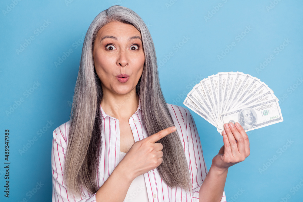 Portrait of beautiful elderly retired pensioner trendy mazed woman showing cash isolated over bright blue color background