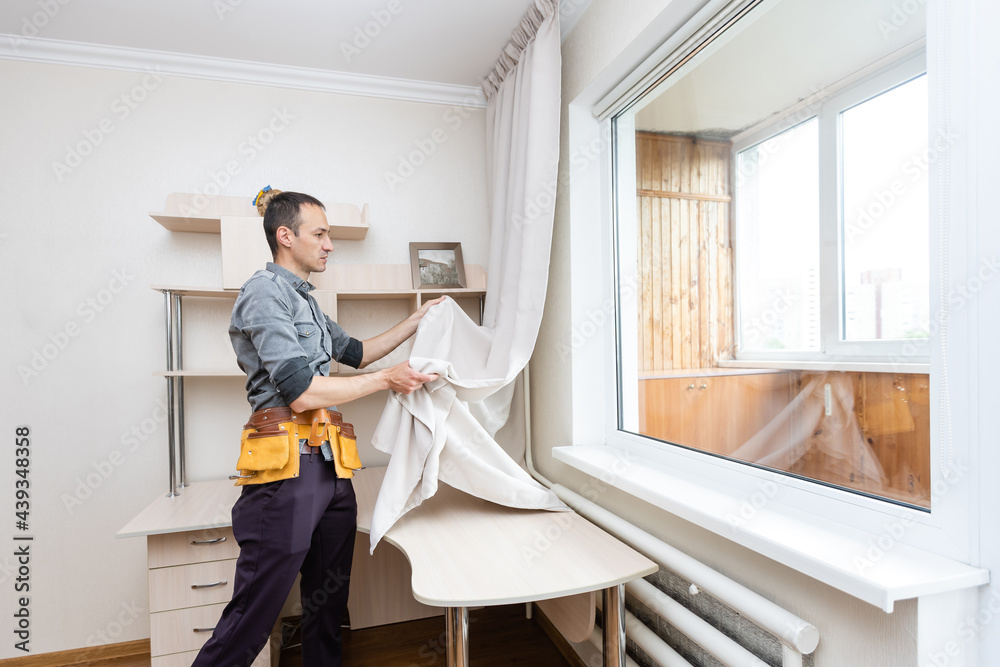 A handyman installing new cornice for curtains, home repair and renovation works A handyman installing new cornice for curtains, home repair and renovation works