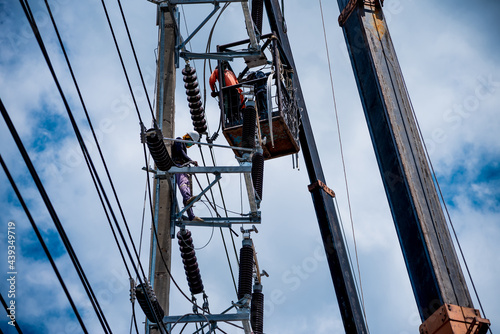 Electricians are climbing on electric poles to install and repair power lines.