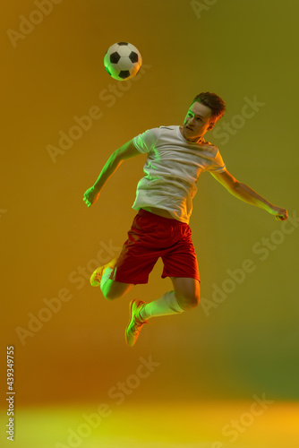 Young caucasian man, male soccer football player training isolated on gradient yellow green background in neon light © master1305