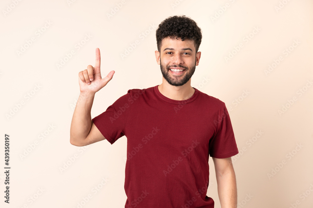 Young Moroccan man isolated on beige background pointing up a great idea Young Moroccan man isolated on beige background pointing up a great idea