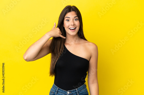 Young Brazilian woman isolated on yellow background making phone gesture. Call me back sign