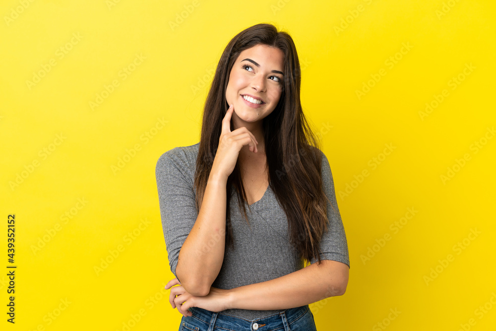 Young Brazilian woman isolated on yellow background thinking an idea while looking up Young Brazilian woman isolated on yellow background thinking an idea while looking up