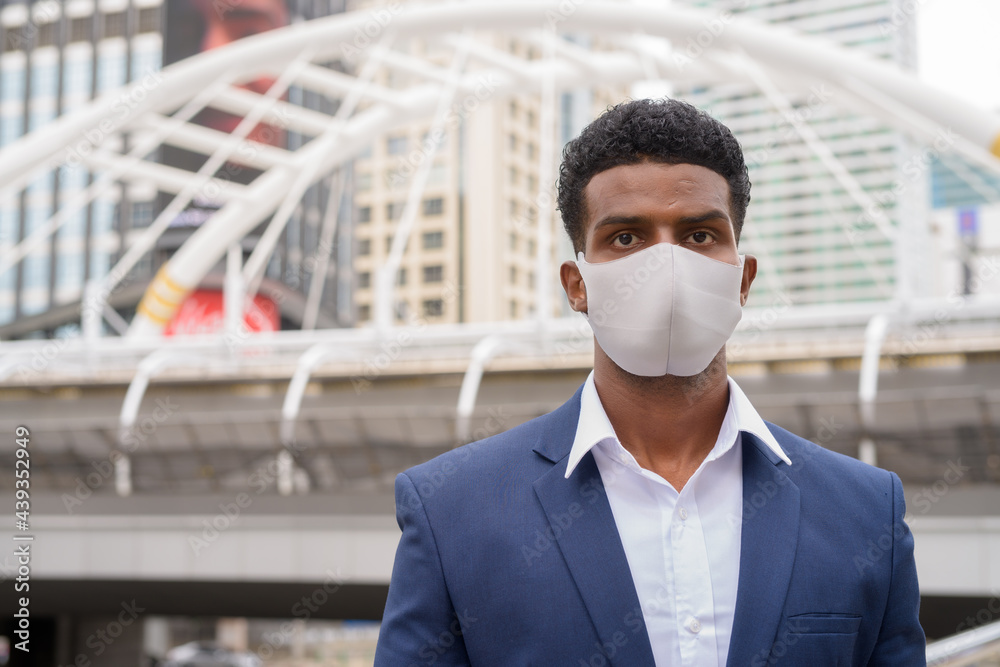 Portrait of African businessman wearing face mask outdoors