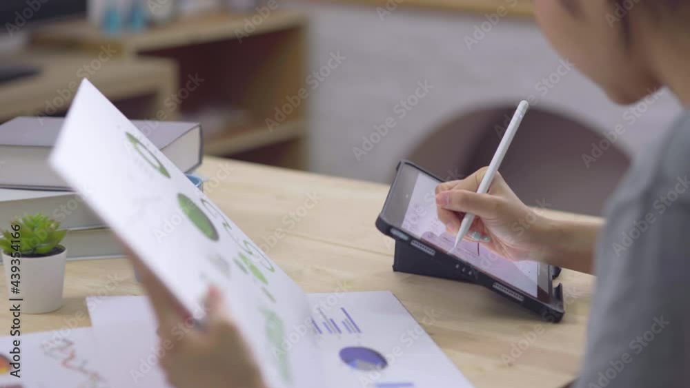 Young businesswoman sitting and using digital tablet learning and studying graph for her finance while using chart for stock marketing working at home office