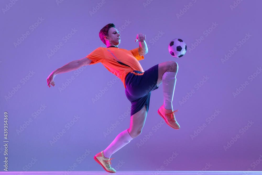 One male soccer football player in action and motion isolated on gradient lilac pink background in neon light