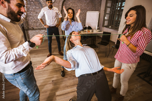 Group having fun together with limbo game at office party.