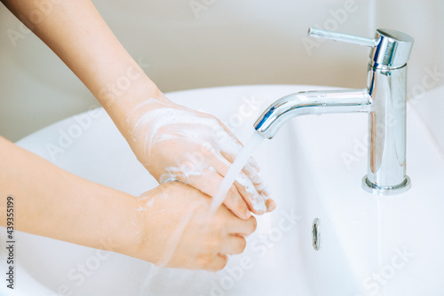 Woman hands are joined together (focus at faucets) and catch the water from the faucet to wash hands, Concept of protection or prevention coronavirus or Covid19 by washing hands frequently.