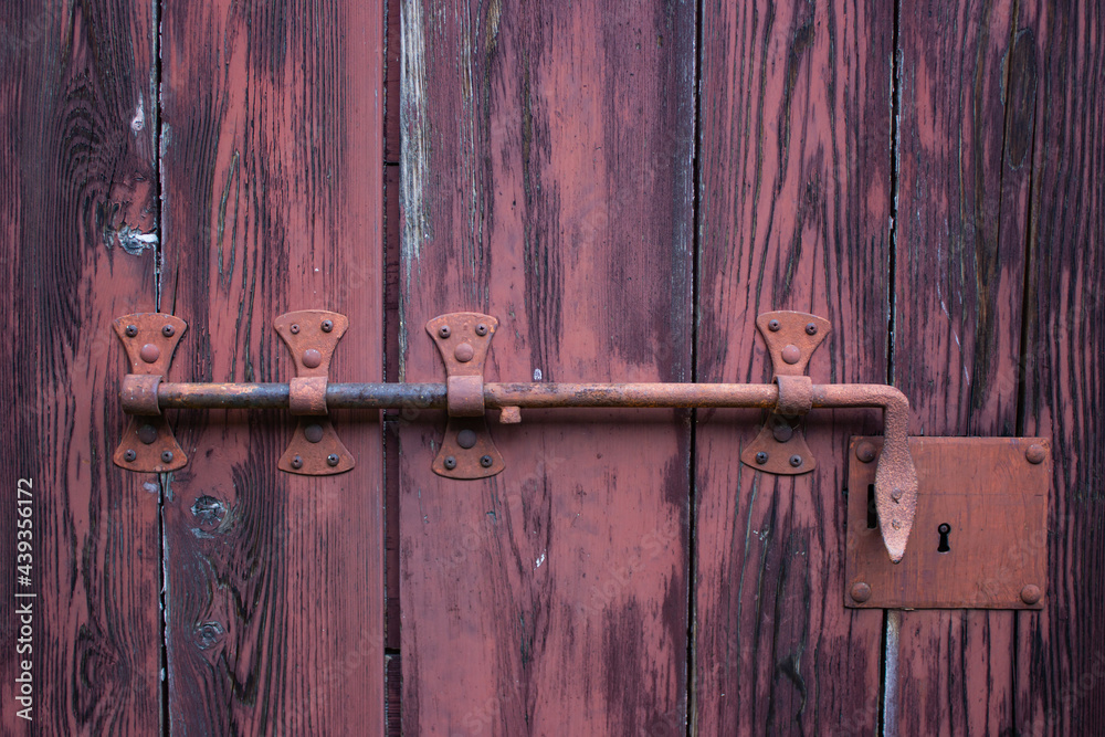 Detail of an ancient red door with a bar. Detail of an ancient red door with a bar.