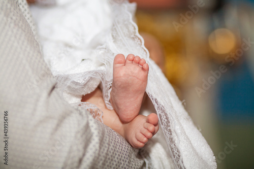Obraz na płótnie The sacrament of the baptism of a child in an Orthodox church, the baby's feet in a white veil close-up