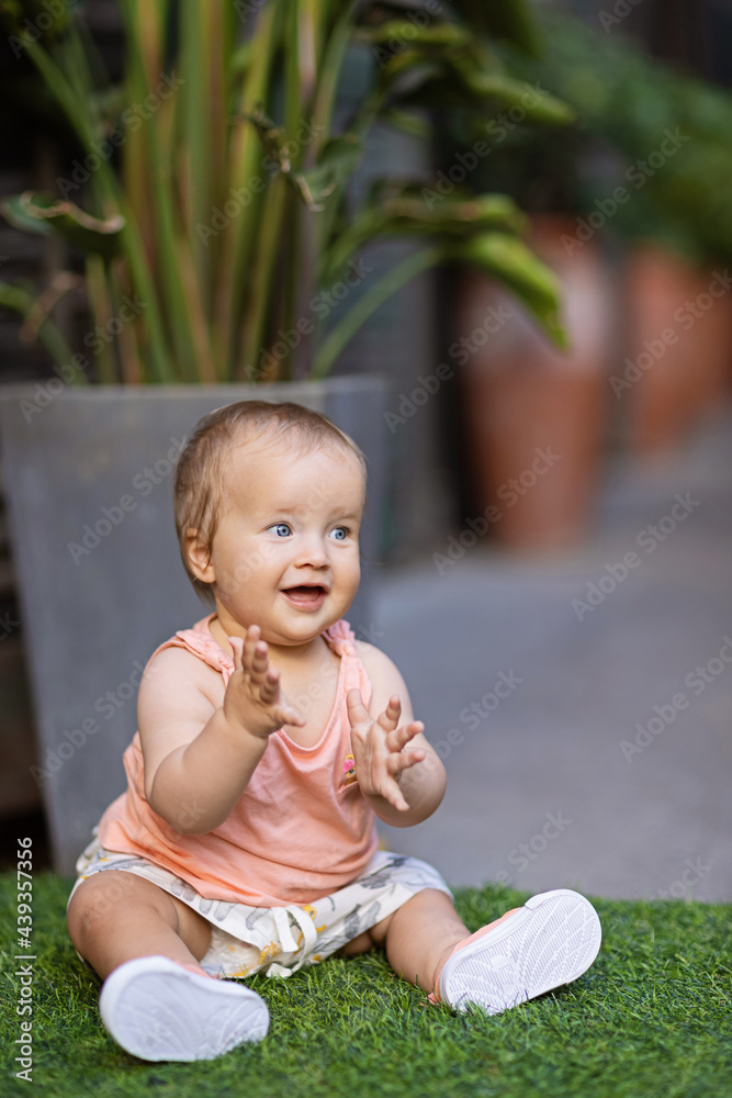 Portrait of cute little caucasian baby girl ten months old playing in summer park. Stylish infant with blonde hair and blue eyes wearing fashionable clothing. Happy childhood and baby healthcare Portrait of cute little caucasian baby girl ten months old playing in summer park. Stylish infant with blonde hair and blue eyes wearing fashionable clothing. Happy childhood and baby healthcare