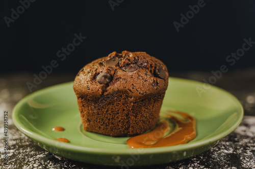 Homemade chocolate chips muffin with caramel on a green dish served gourmet