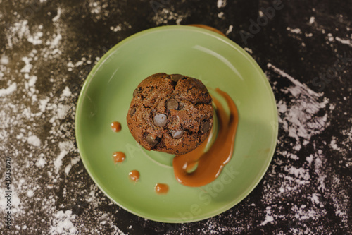 Homemade chocolate chips muffin with caramel on a green dish served gourmet