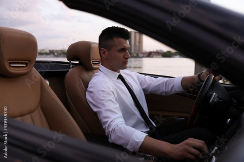 Stylish handsome businessman driving luxury convertible car © New Africa