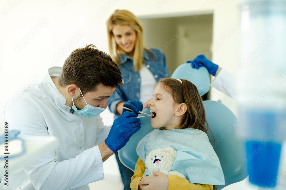 Male doctor with instruments in the hands looking girls teeth. Male doctor with instruments in the hands looking girls teeth.