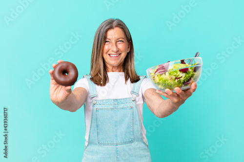 iddle age pretty woman with a donut and a salad. diet concept photo