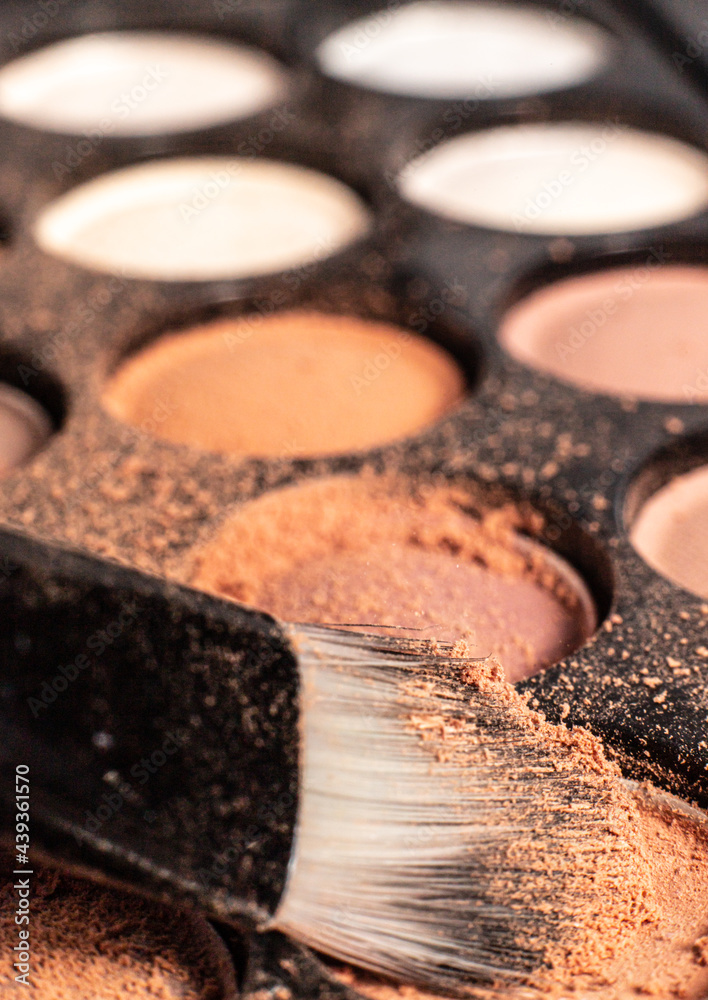 Fototapeta premium eye shadow is close. A makeup brush with eye shadow on it scatters the grains. macro palettes with shadows
