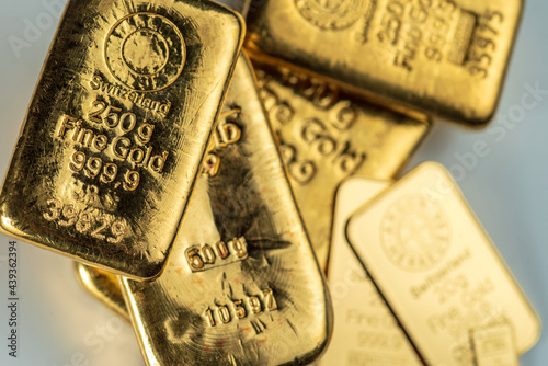Several cast and minted gold bars on a on grey background. Selective focus. photo