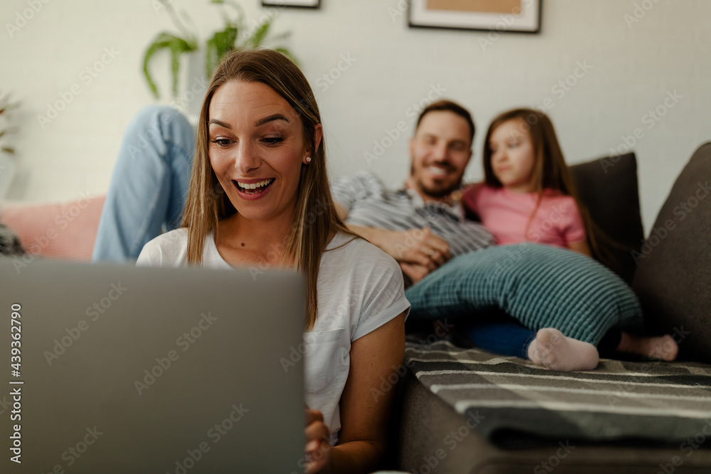 Mother sits on the floor and celebrates the good news at work, while the father and daughter cuddle. Mother sits on the floor and celebrates the good news at work, while the father and daughter cuddle.