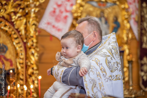 Religious sacrament - the baptism of a child, a little boy in the arms of the godmother, a close-up portrait of a baby. photo