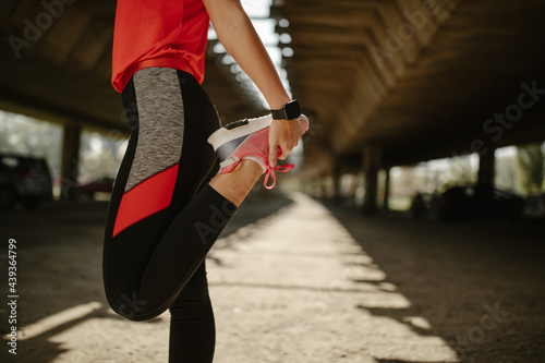 Sporty woman stretching her legs outside. Fitness woman relaxing her leg muscles.