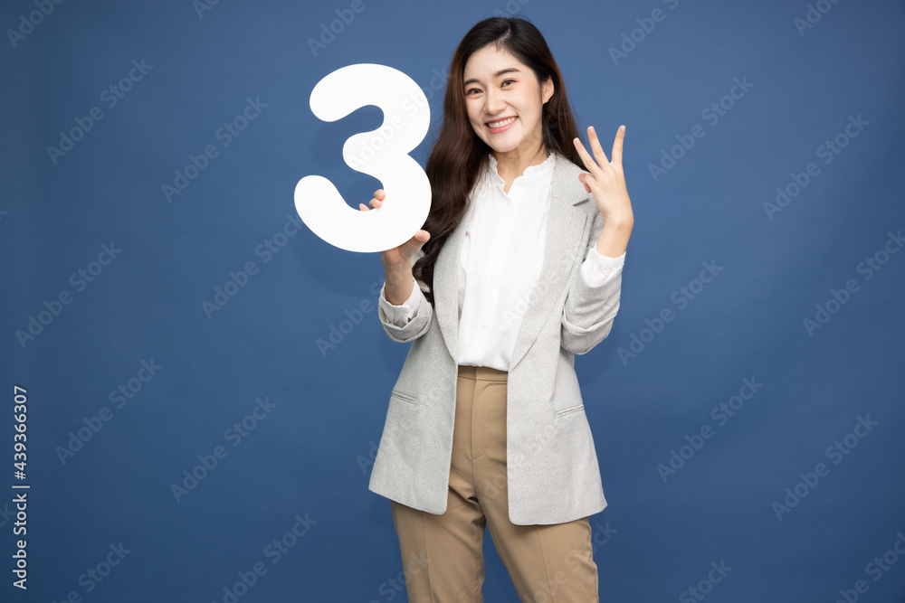 Young beautiful Asian woman showing number 3 and pointing up with finger number three isolated on blue background Young beautiful Asian woman showing number 3 and pointing up with finger number three isolated on blue background