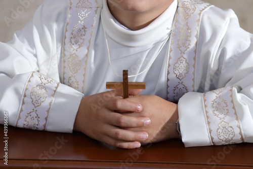 Ragazzo con il crocifisso tra le mani indossa la tunica per prendere il sacramento della comunione photo