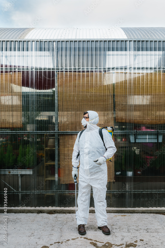 Man wearing a professional protective coverall to fumigate plant Man wearing a professional protective coverall to fumigate plant