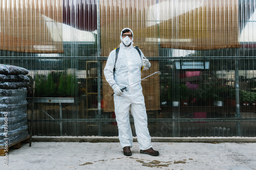 Man wearing a professional protective coverall to fumigate plant photo