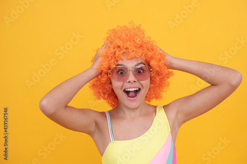 birthday party. funny kid in curly clown wig. having fun. surprised child
