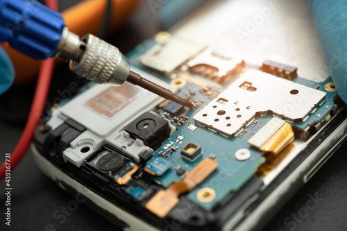 Technician repairing inside of mobile phone by soldering iron. Integrated Circuit. the concept of data, hardware, technology.