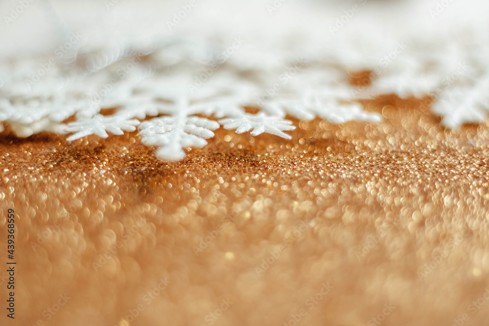 artificial snowflakes are arranged in a row on a golden background. Place for text