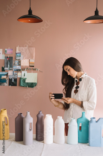 Young Woman Photographing Colored Plastic Bottles  photo