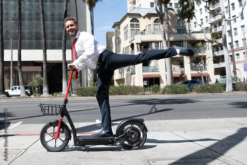 happy man businessman riding electro scooter on cityscape background, rental transportation. photo