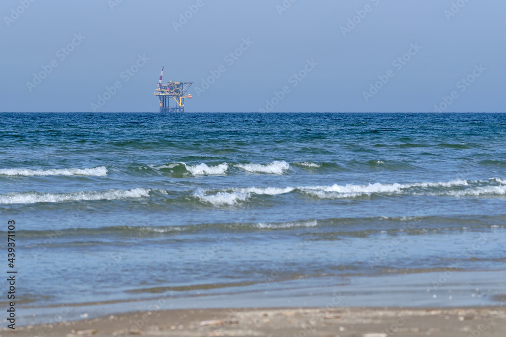 Ameland,Netherlands April 20,2021-NAM, Oil rig, offshore platform with beach, sand and surf. Natural gas extraction in the Wadden-North Sea Region, Wadden Island, nature conservation area:Het Oerd.