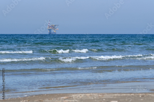 Ameland,Netherlands April 20,2021-NAM, Oil rig, offshore platform with beach, sand and surf. Natural gas extraction in the Wadden-North Sea Region, Wadden Island, nature conservation area:Het Oerd.