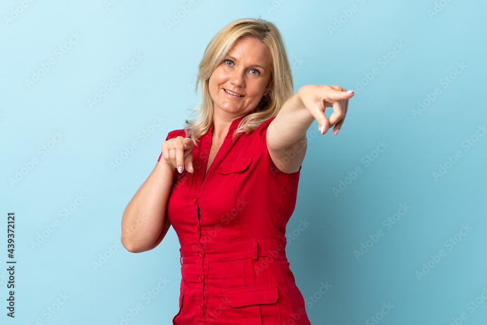 Middle age woman isolated on blue background pointing front with happy expression