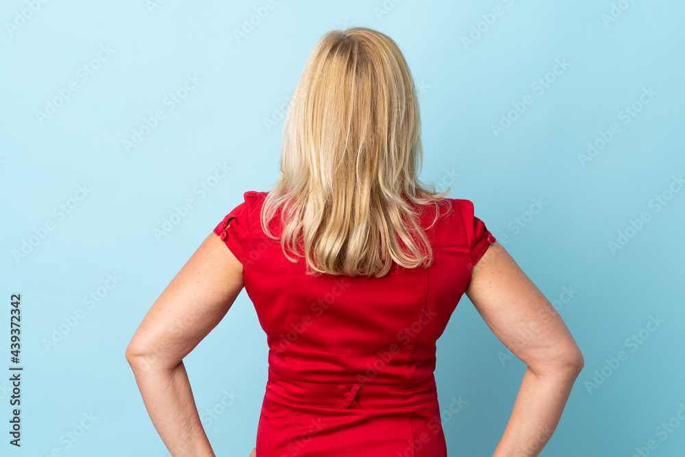 Middle age woman isolated on blue background in back position