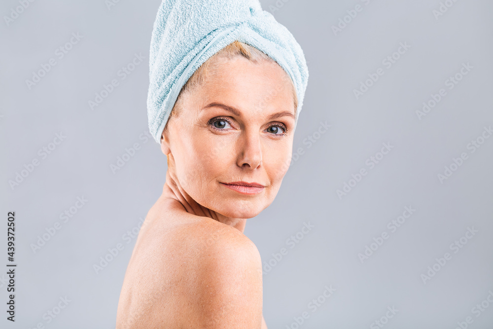 Portrait of smiling senior woman feeling soft skin with hand after spa bath. Mature woman draped in towel looking at camera. Lady in bathrobe after shower isolated over white background. Portrait of smiling senior woman feeling soft skin with hand after spa bath. Mature woman draped in towel looking at camera. Lady in bathrobe after shower isolated over white background.