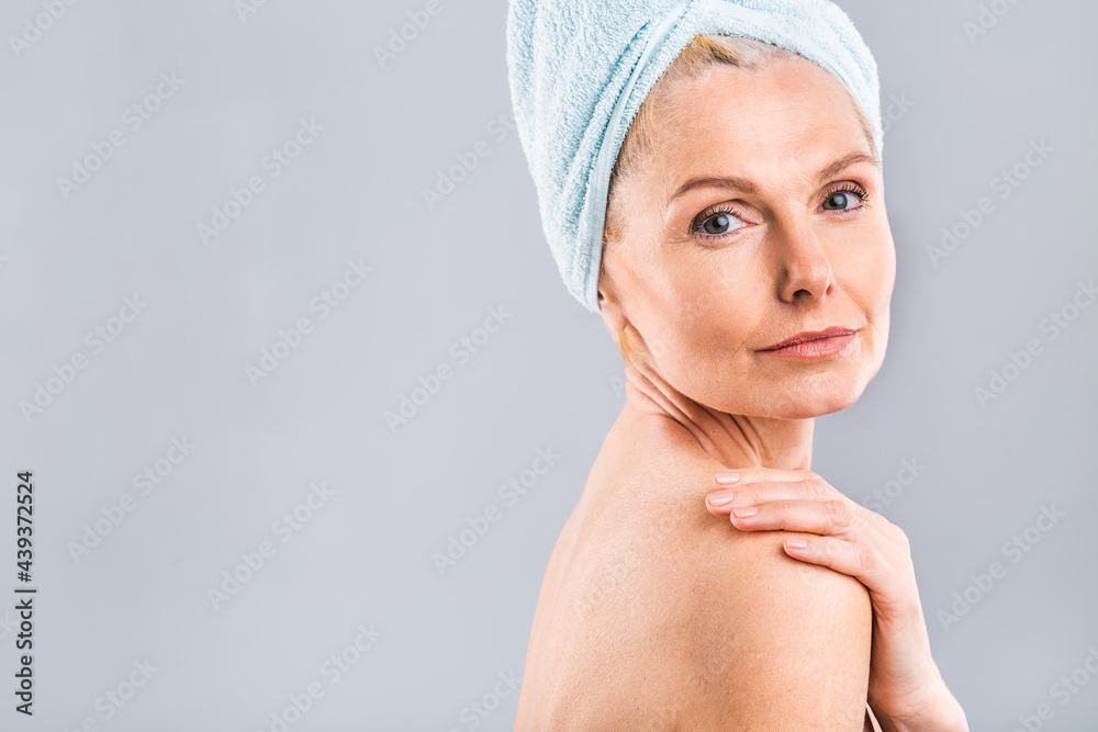 Portrait of smiling senior woman feeling soft skin with hand after spa bath. Mature woman draped in towel looking at camera. Lady in bathrobe after shower isolated over white background. Portrait of smiling senior woman feeling soft skin with hand after spa bath. Mature woman draped in towel looking at camera. Lady in bathrobe after shower isolated over white background.
