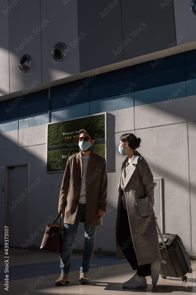 Couple with luggage standing on station during pandemic Couple with luggage standing on station during pandemic