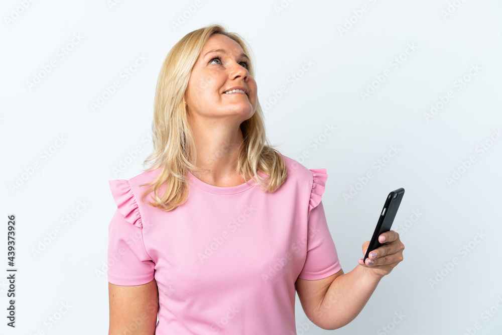 Middle age using mobile phone isolated on white background looking up while smiling Middle age using mobile phone isolated on white background looking up while smiling