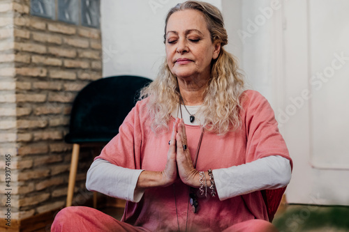 senior woman doing yoga with hands in prayer mode photo